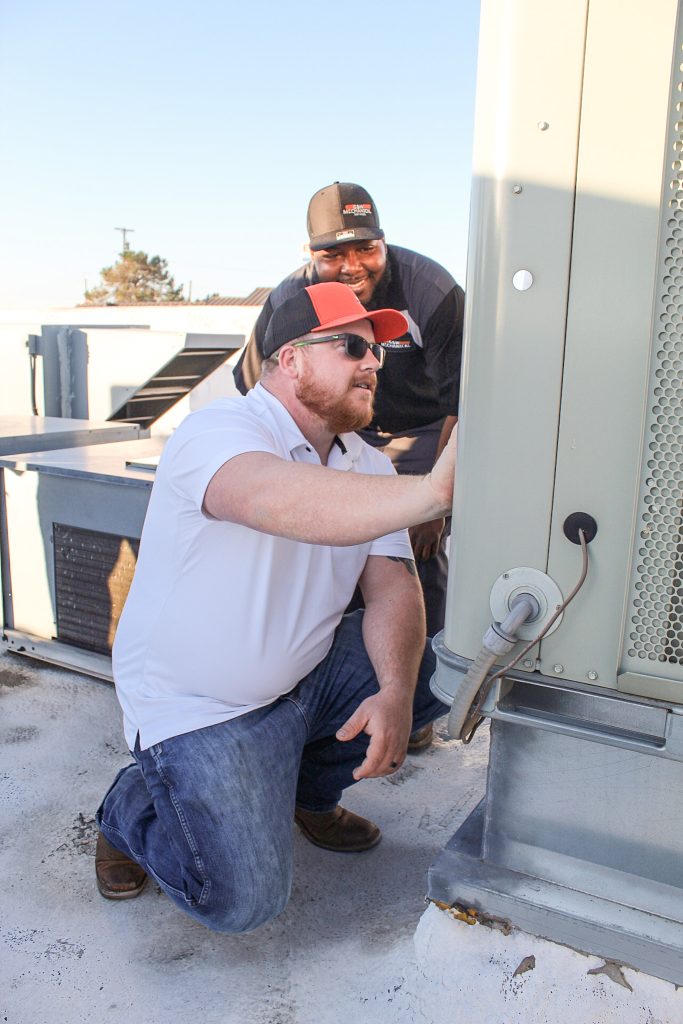 G&W Mechanical Services technicians inspecting a restaurant's rooftop HVAC unit